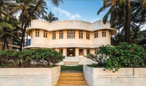 Mumbai’s luxury real estate market has once again made headlines with a deal that blends legacy, location, and exclusivity. A rare sea-facing heritage bungalow in Juhu, fondly known as Leela; has changed hands in a transaction valued at a staggering ₹221 crore, making it one of the most remarkable property deals in recent times. A Landmark Deal in Mumbai’s Premium Property Market In a city where space is scarce and sea-facing homes are even rarer, this acquisition stands out. The historic bungalow, owned by the well-known Nanavati family, has been purchased by Notandas Realty, part of the reputed Mahesh Notandass Jewellers Group. Situated along the prestigious Juhu Tara Road, just steps away from the ever-popular Juhu Beach, the property enjoys uninterrupted sea views—something that instantly elevates its desirability in Mumbai’s ultra-luxury housing segment. The deal, finalized on April 22, 2026, reportedly followed strong interest from multiple developers and high-net-worth individuals. Ultimately, Notandas Realty secured the property, underlining the continued appetite for trophy assets in Mumbai’s prime micro-markets. What Makes ‘Leela’ So Special? Unlike modern glass towers dominating Mumbai’s skyline, Leela carries a distinctive old-world charm. Built in the 1950s, the bungalow reflects elegant Art Deco architecture—a style that is both rare and culturally significant in today’s context. Spread across a plot of approximately 14,500+ sq ft, the property offers a built-up area of around 8,480 sq ft. But what truly sets it apart isn’t just the numbers—it’s the lifestyle it represents. Key Highlights of the Property • Expansive 6-bedroom layout designed for large family living • Multiple living and sitting areas, offering both privacy and openness • Sea-facing balconies and verandahs that capture Mumbai’s coastal beauty • A sprawling private garden of nearly 5,000 sq ft • A large terrace space exceeding 2,500 sq ft • Dedicated staff quarters and parking for four vehicles The bungalow is thoughtfully structured across levels. The ground floor houses primary living spaces including bedrooms, a dining area, and kitchen. The upper floor accommodates additional bedrooms and lounges, while the top level opens up into a generous terrace overlooking the Arabian Sea. Pricing Insights: How Premium Was This Deal? While the total transaction value of ₹221 crore is eye-catching, breaking it down offers deeper insight into Mumbai’s luxury pricing dynamics. • On a built-up basis, the deal translates to approximately ₹2.6 lakh per sq ft • On land area, it comes to roughly ₹1.5 lakh per sq ft Interestingly, while this is among the most expensive bungalow deals, it still falls slightly below the per sq ft benchmark set by Uday Kotak’s sea-facing purchase at Worli. However, direct comparisons are tricky. Properties like Leela are one-of-a-kind assets, where valuation goes beyond just numbers, factoring in heritage status, location rarity, and emotional value. The Legacy Behind the Property The bungalow isn’t just about luxury, it carries a rich legacy. Built as a joint family residence, it once housed multiple generations of the Nanavati family under one roof. Its name is believed to be inspired by Sir Manilal Balabhai Nanavati, a prominent figure who served as Deputy Governor of the Reserve Bank of India during the pre-independence era. The Nanavati family itself is widely recognized for its association with Nanavati Hospital, adding further prominence to the property’s history. Understanding the Heritage Tag One of the most crucial aspects of this transaction is the bungalow’s classification as a Grade IIB heritage property. So what does that mean? Heritage properties in Mumbai are protected under strict regulations due to their architectural or historical importance. For buyers, this comes with both prestige and limitations: • Structural changes and redevelopment are tightly controlled • Demolition for high-rise construction is not immediately permissible • Restoration and maintenance must adhere to heritage guidelines This means that while Notandas Realty now owns a prized asset, its future use will need to align with regulatory approvals. In the long term, if policies evolve or permissions are granted, redevelopment possibilities could be explored—but that remains uncertain. Why Juhu Continues to Attract Ultra-Luxury Buyers Juhu has long been one of Mumbai’s most coveted residential pockets. Its combination of beachfront living, celebrity homes, and strong social infrastructure keeps it firmly in demand. From high-profile residents to proximity to key commercial hubs, Juhu offers a rare mix of exclusivity and accessibility. Add to that the emotional appeal of living by the sea, and it’s easy to see why properties here command such extraordinary valuations. A Deal That Reflects More Than Just Price This transaction is more than just a high-value sale, it’s a reflection of how Mumbai’s real estate market continues to value legacy assets. In a landscape dominated by redevelopment and vertical growth, standalone heritage homes like Leela are becoming increasingly rare. For investors and developers alike, such properties are not just purchases, they are long-term strategic assets, blending heritage, prestige, and potential.